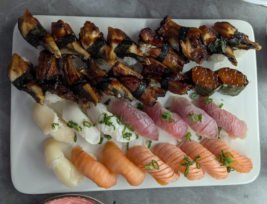 A picture of a plate of nigiri sushi, with eel, tuna and salmon.