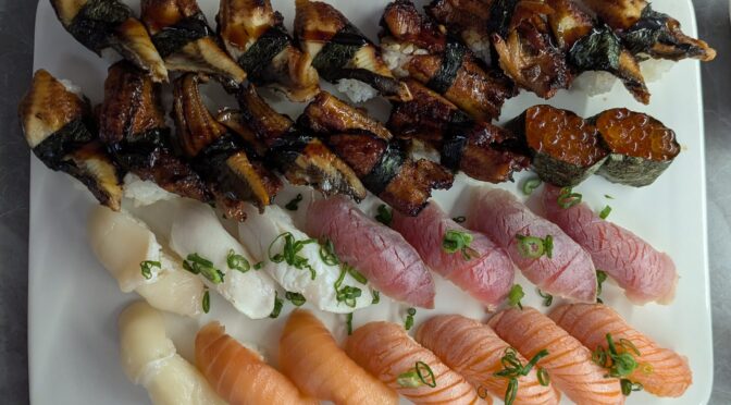 A picture of a plate of nigiri sushi, with eel, tuna and salmon.